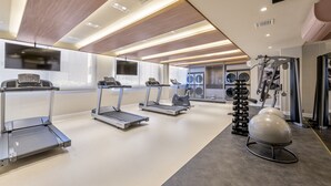 Un gimnasio moderno con cintas de correr, una bicicleta estática y una máquina de remo.