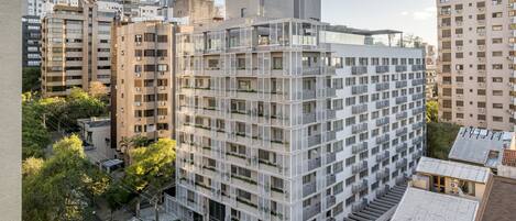 A modern multi-story building with a grid-like facade, balconies, and a mix of residential and commercial spaces.