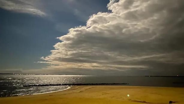 En strand med klar himmel og en stor skyformation.
