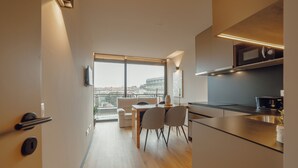 Een moderne keuken met een eethoek, grote ramen en uitzicht op de stad.