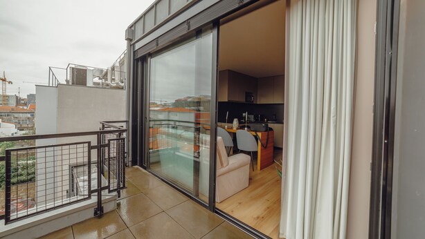 Een modern appartement met een balkon, grote schuifdeuren en uitzicht op de stad.