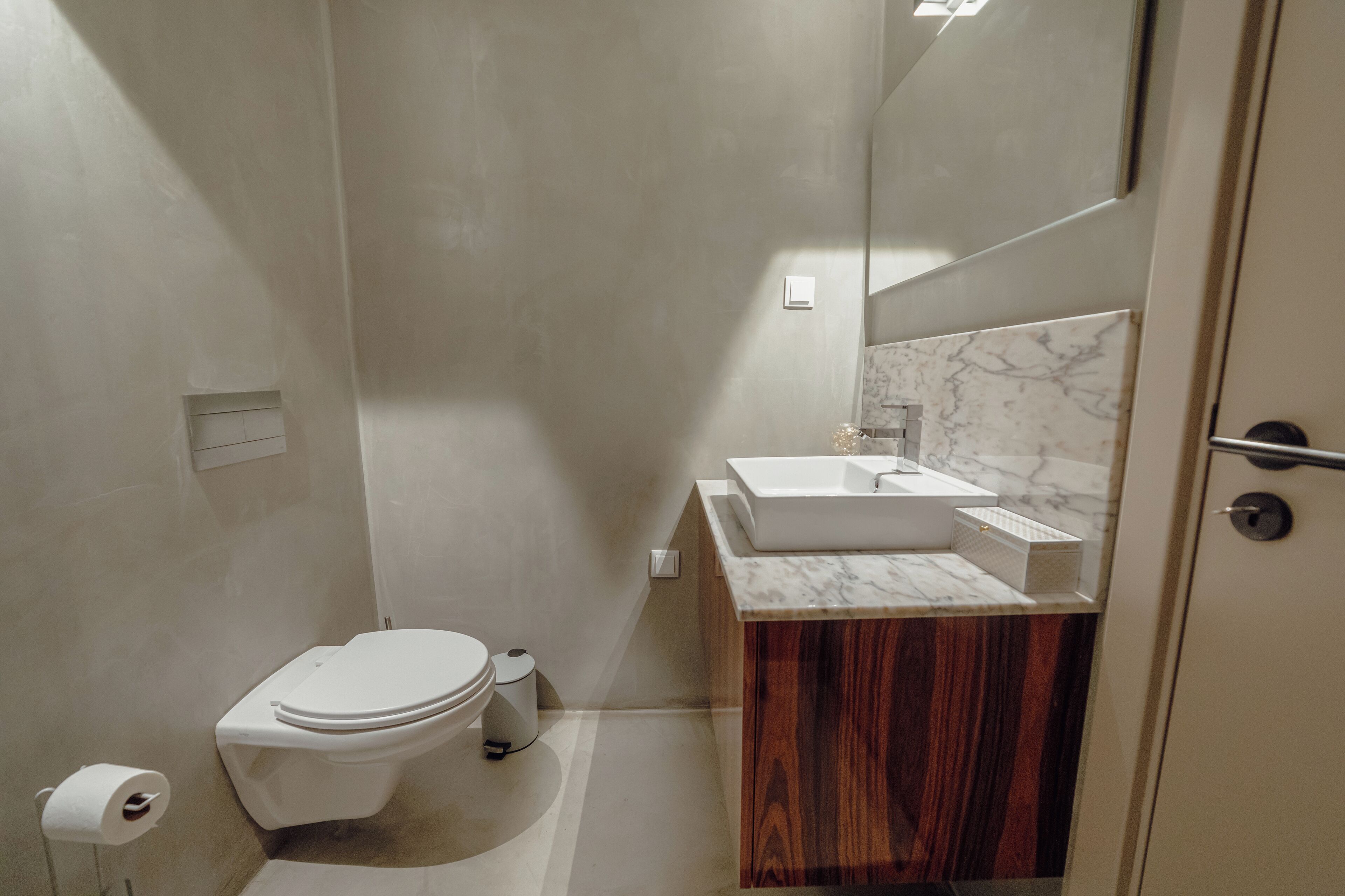 A modern bathroom with a toilet, sink, and mirror.