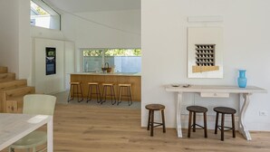 Una cucina moderna con isola centrale, sgabelli di legno e un tavolo bianco con sedute.