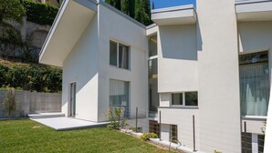 Una moderna casa a due piani con tetto piatto, ampie finestre e un prato ben curato.
