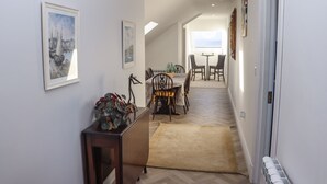 A hallway leading to a dining area with a view, a radiator, and framed artwork on the walls. - Lakeview Retreat (Garrykennedy)