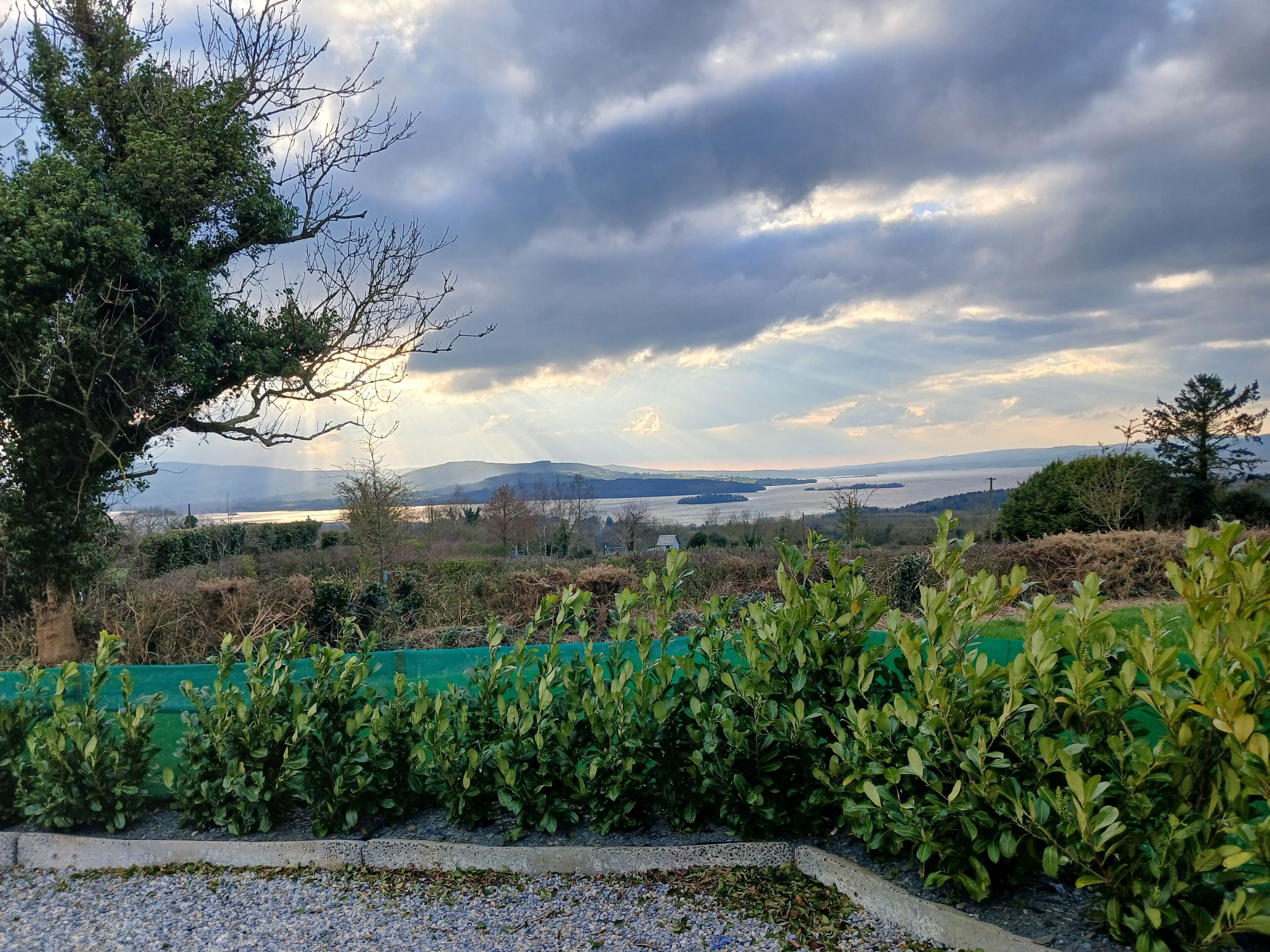 Ein angelegter Garten mit Blick auf einen See und ferne Berge.