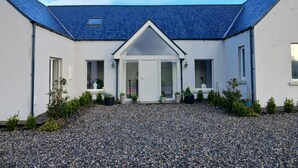A modern house with a gravel driveway, a central entrance with a white door, and a blue roof. - Lakeview Retreat (Garrykennedy)
