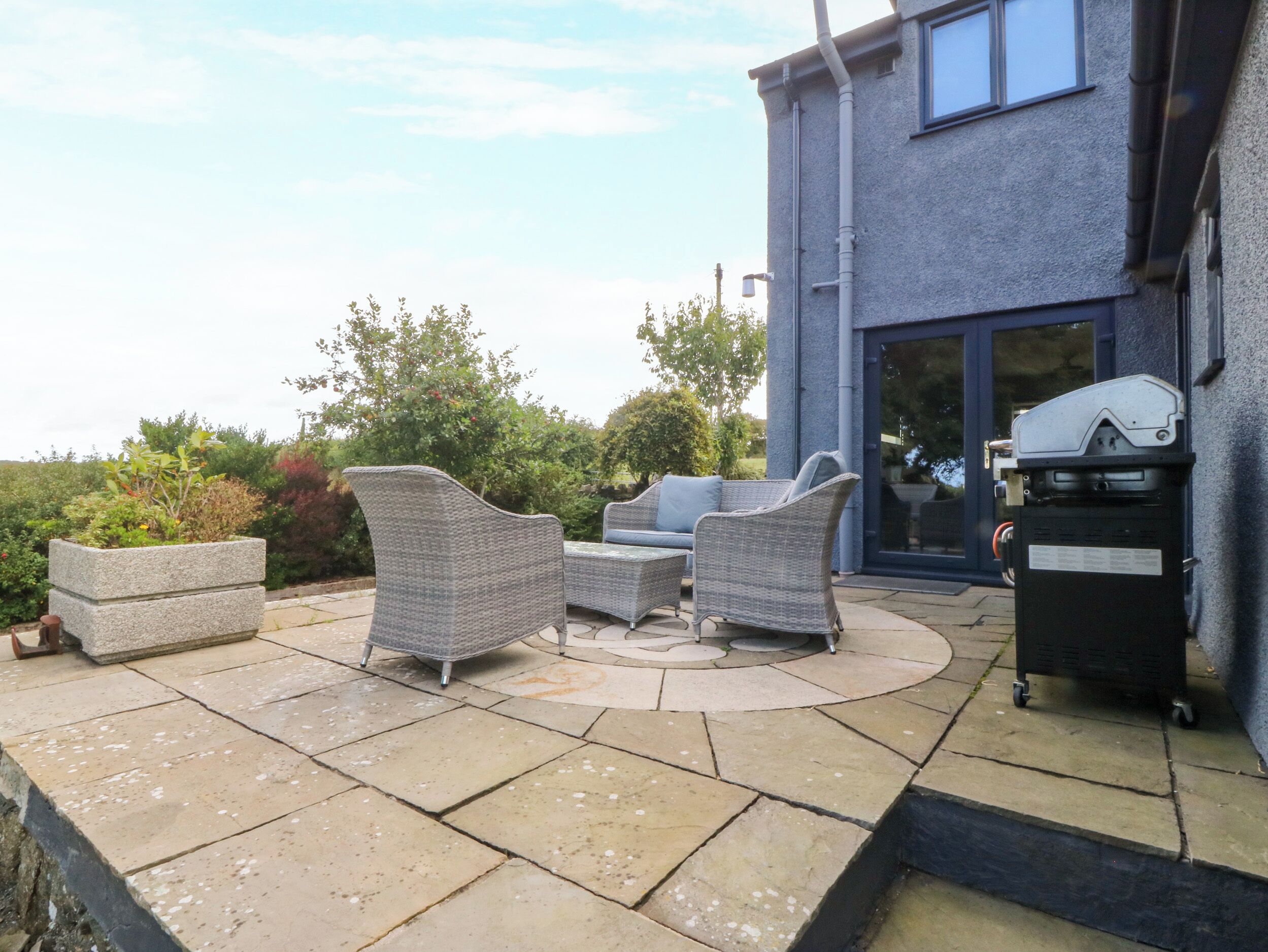 An outdoor patio with wicker furniture and a barbecue grill.
