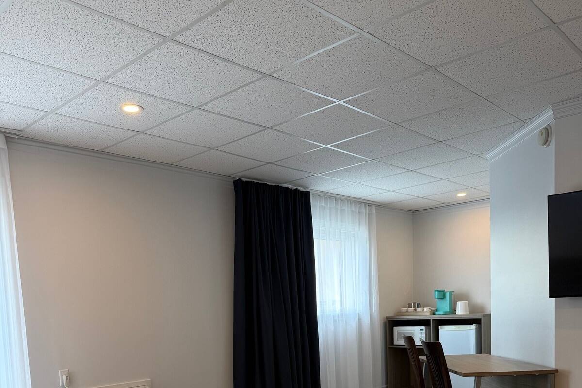 Una habitación de hotel con cama, escritorio, silla, televisión y ventana con cortinas.