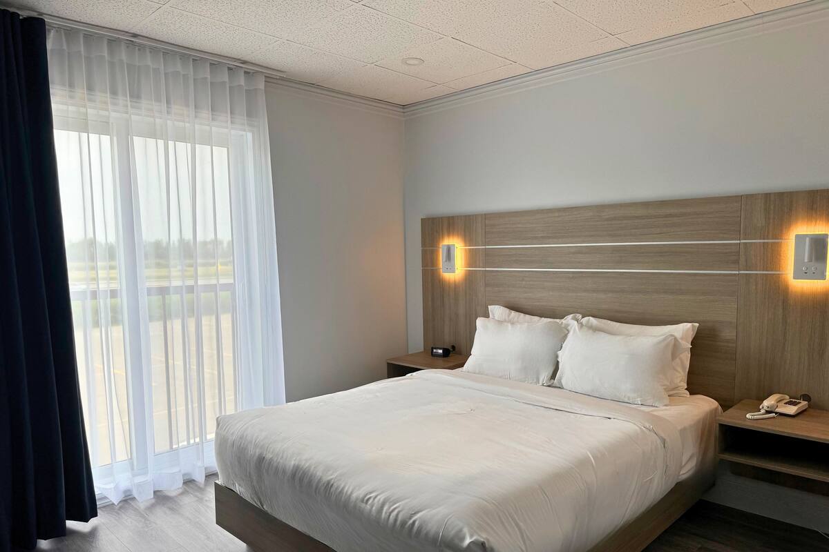 Habitación de hotel con una cama grande, una mesita de noche con teléfono y una lámpara de pared.
