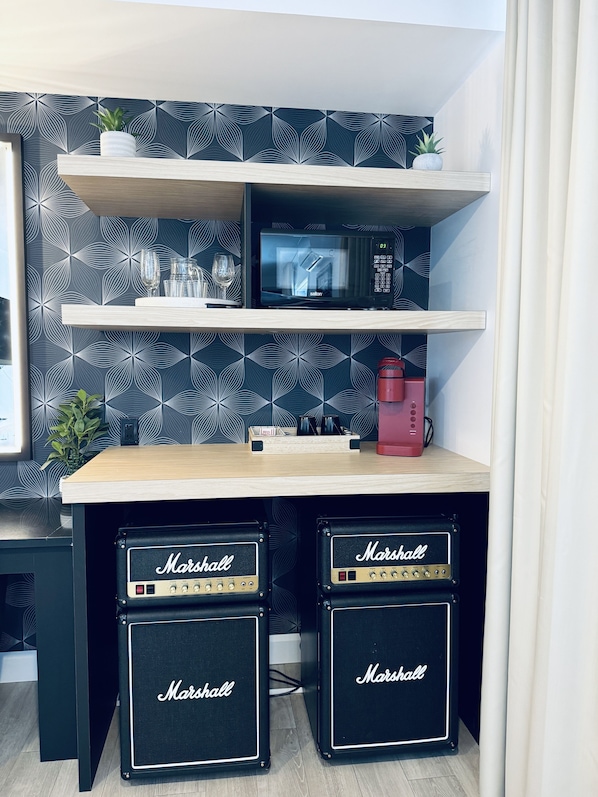 A kitchen area with a microwave, two Marshall amplifiers, a coffee maker, and decorative items on shelves. - Hôtel La porte de la Mauricie (Yamachiche)