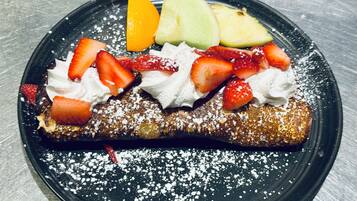 Ein Dessertteller mit einer Crêpe, Erdbeeren und einem Melonenscheibchen.
