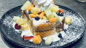 A dessert plate with fruit and whipped cream on a black plate.