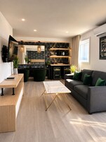 A modern living room with a sofa, coffee table, and a kitchen area with built-in appliances.