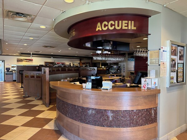 Un área de recepción con un mostrador curvo, un cartel que dice "ACCUEIL" y un mostrador de registro en el fondo.