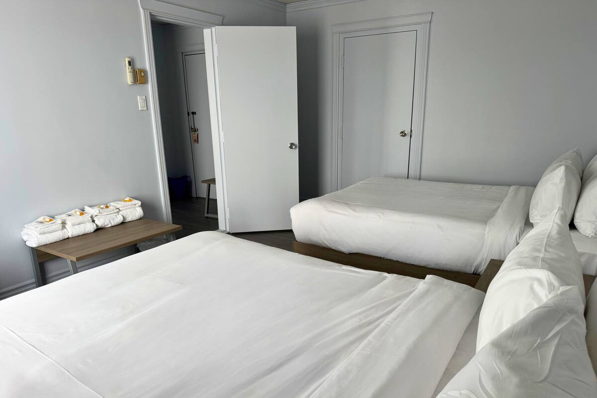 Habitación de hotel con dos camas, una mesita con toallas y una puerta que da a otra habitación.