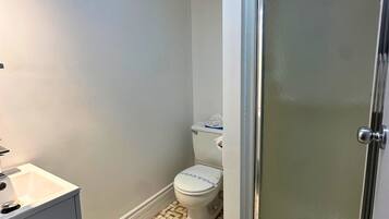 Ein Badezimmer mit Toilette, Waschbecken und einer Dusche mit Glastür.