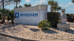A sign for Wyndham Ocean Ridge Vacation Ownership Resort with a clear sky and palm trees in the background. - 2BR/2BA Condo with golf views ~ Edisto On My Mind (Edisto Island)