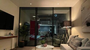 Una sala de estar moderna con sofá, mesa de centro y televisor montado en la pared.