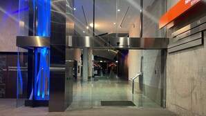 Entrada de un edificio moderno con puertas de vidrio, una pantalla digital y un cartel que anuncia NewAction apartments.