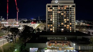 Un hotel de varios pisos con diseño moderno, que cuenta con balcones en cada planta y un área en la azotea con asientos al aire libre.
