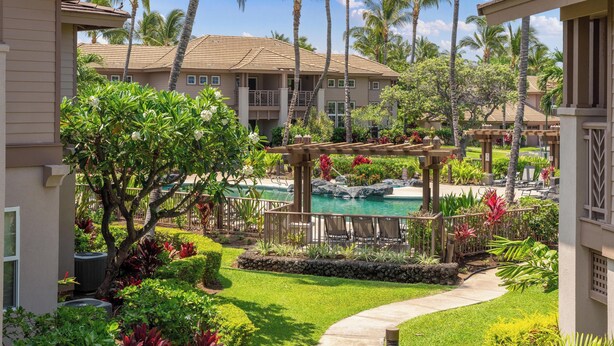 A resort with a swimming pool, palm trees, and a covered patio area.