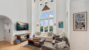 A spacious living room with a large window, a sofa, a coffee table, and a TV.