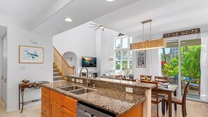 A modern kitchen with granite countertops, a dishwasher, and a dining area with wooden furniture.
