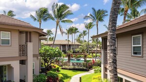 A resort with multiple buildings, a swimming pool, and palm trees.