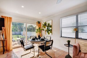 A dining area with a round table, chairs, and a small side table. - Black Flamingo: Flamingo Park Walkable, Pet Friendly, Fenced In Yard
 (West Palm Beach)