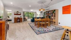 Una sala de estar moderna con comedor, estantería y un amplio ventanal que proporciona luz natural.