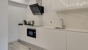 A modern kitchen with white cabinetry, a built-in oven, a coffee maker, and a stainless steel sink. - Torre Palace II by Atlantic Holiday (Camara de Lobos)