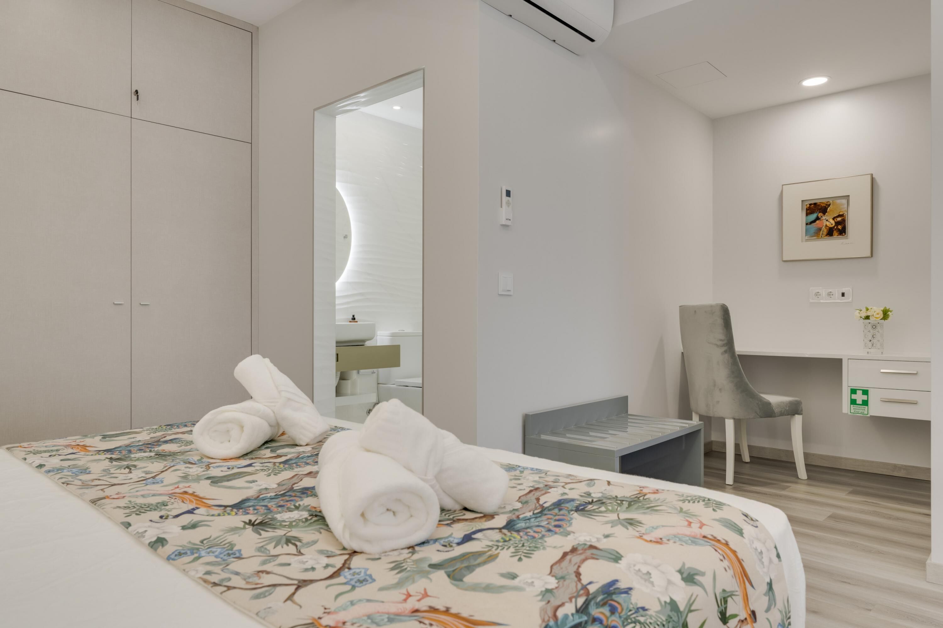 Una habitación de hotel con cama, escritorio, silla y armario.