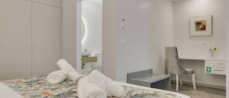 Una habitación de hotel con cama, escritorio, silla y armario.