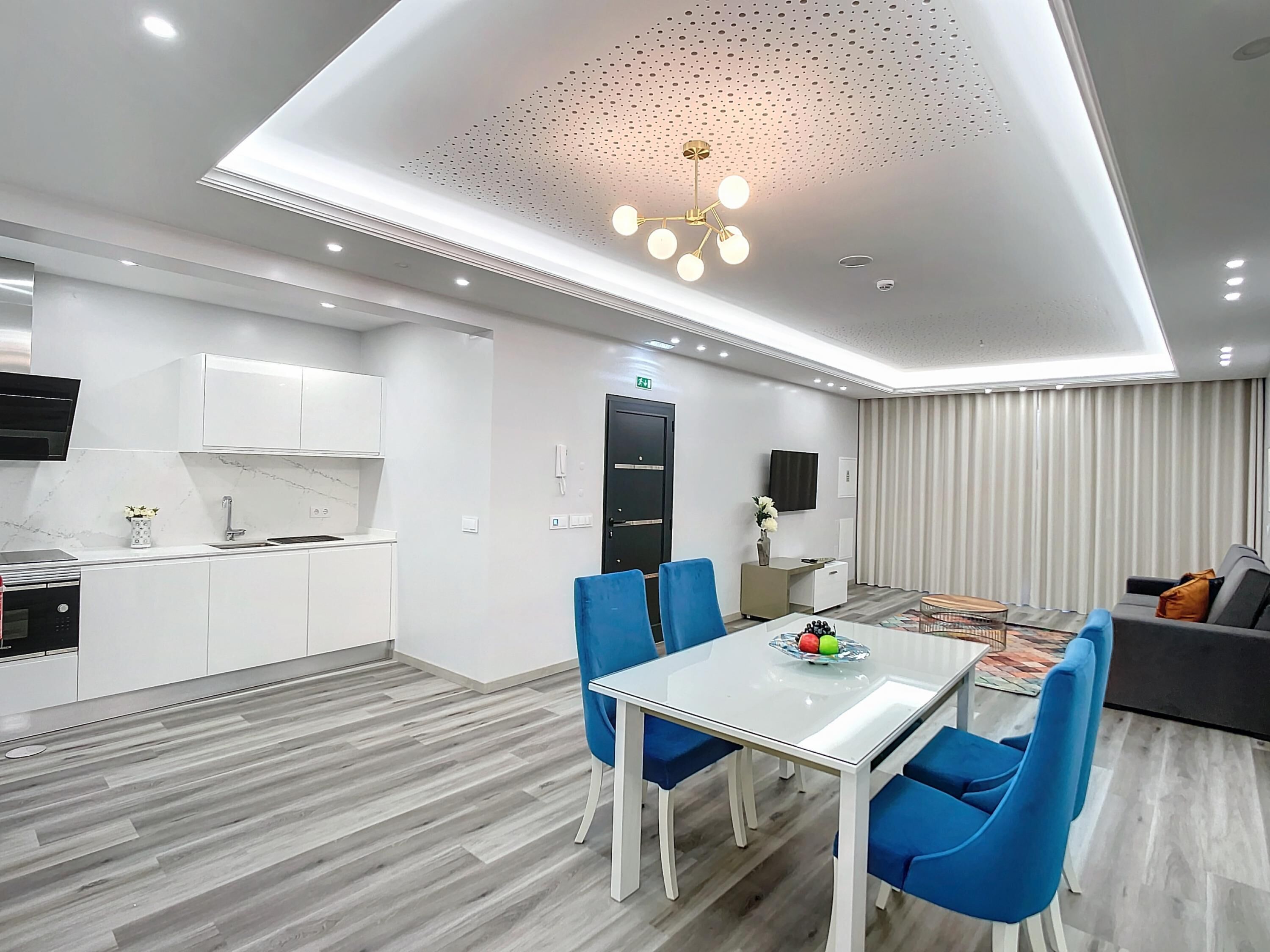 A modern hotel room with a kitchen, dining area, and living space.