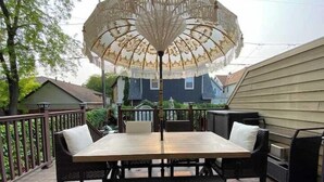 A patio with a table and chairs, an umbrella, and a railing. - Brady Street Luxury | Close to Downtown | Sleeps 8 (Milwaukee)