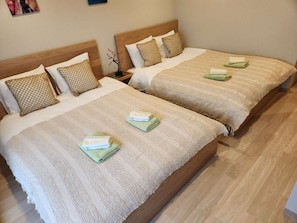 Two double beds with striped bedding and pillows, a nightstand with a lamp, and a wooden floor. - Tamatsukan/ JR Tsuruhashi 8 mins/ Early Check in (Osaka)