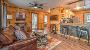 A cozy cabin interior with a living room, dining area, and kitchen. - Pet Friendly Creekside Cabin + Hot Tub + Fire Pit (Mineral Buff)