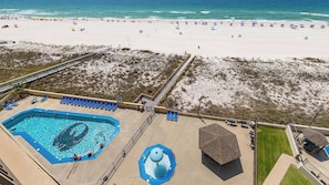 Een strandresort met een zwembad, strandparasols en een uitkijktoren voor de badmeester.