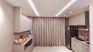 A compact kitchen with a built-in refrigerator, a microwave, and a sink.