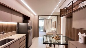 A modern kitchen with a built-in refrigerator, a glass dining table, and a seating area with a sofa and chairs.