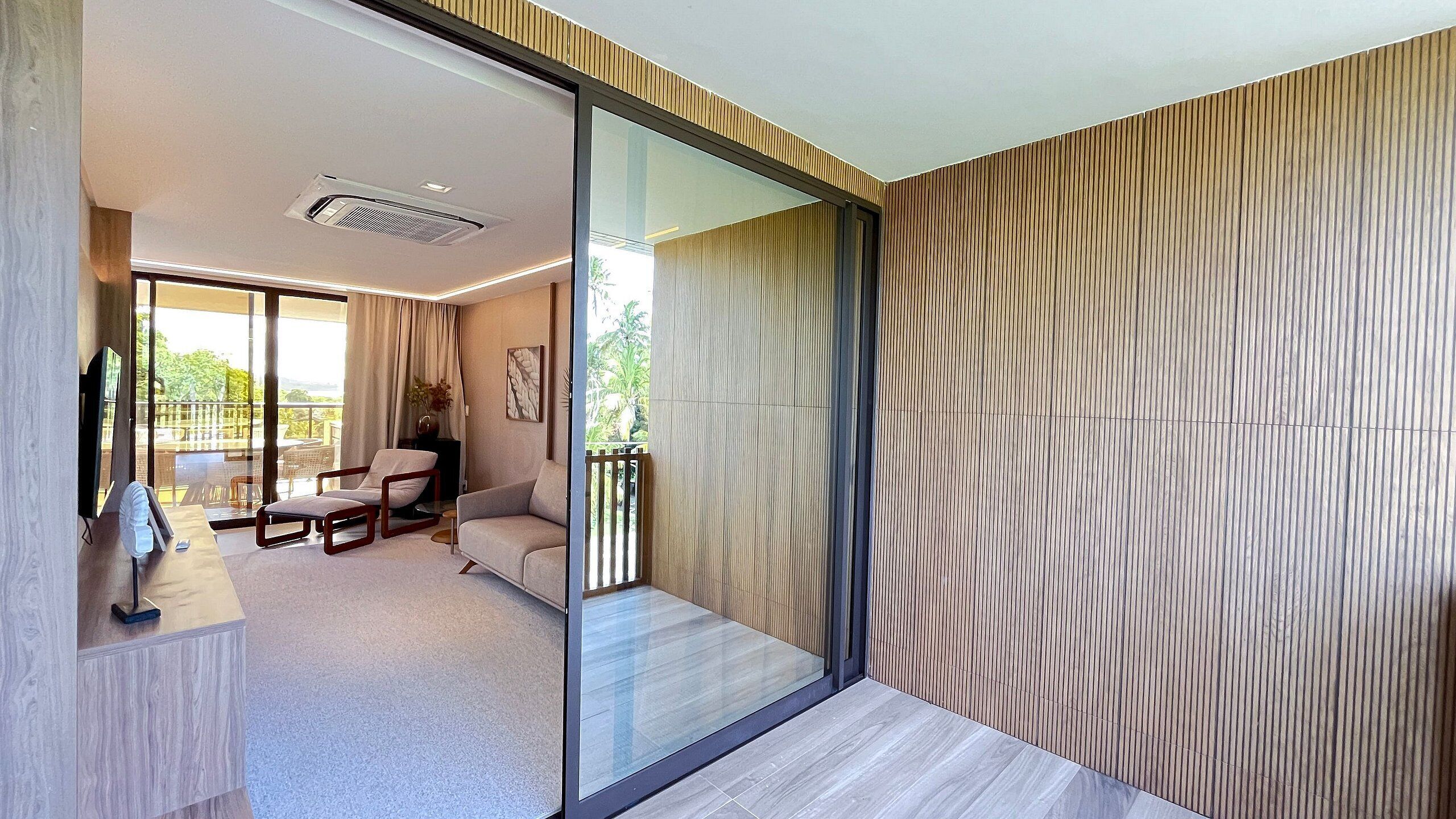 A modern interior with a glass partition, a sofa, a chair, and a small table.
