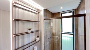 Ein modernes Badezimmer mit Glasdusche, einem Holzwaschtisch und einem großen Fenster.