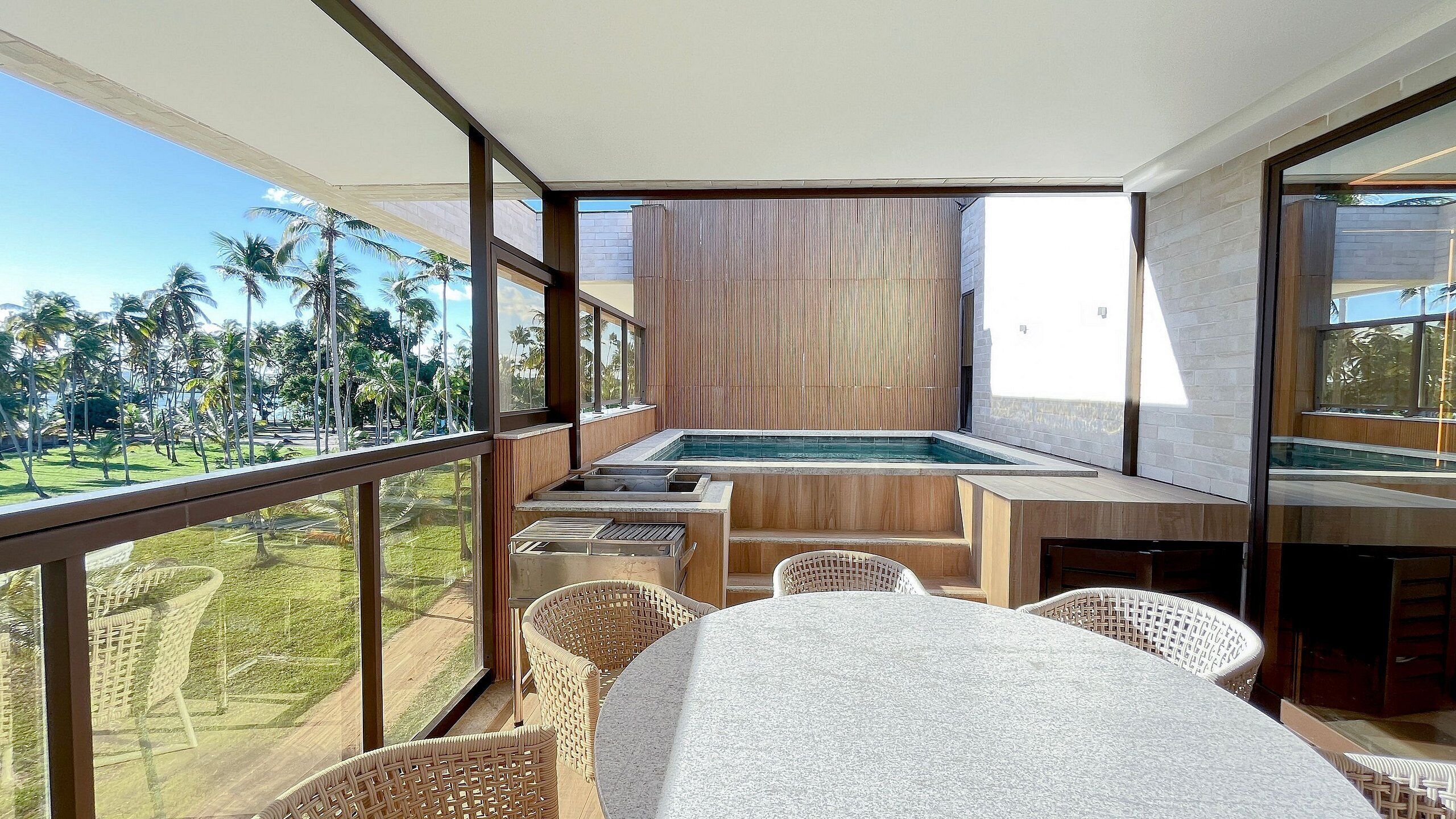 Un balcón con piscina, mobiliario de mimbre y vistas a palmeras.