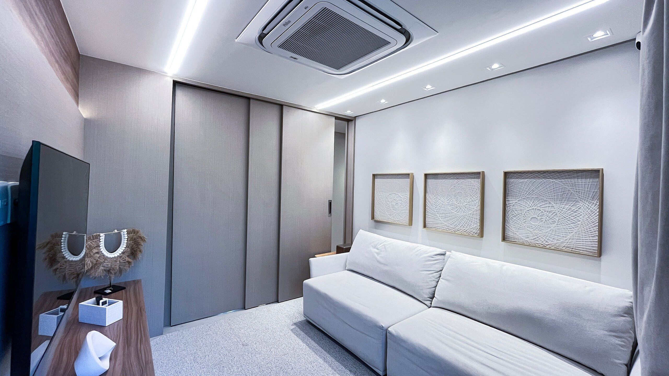 A modern bedroom with a sofa, a mirror, and artwork on the wall.