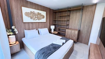 Ein modernes Schlafzimmer mit einem großen Bett, einem Nachttisch, einer Lampe, einem Wanddekor und integrierten Regalen.