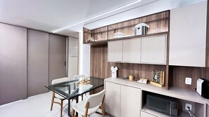 Eine moderne Küche mit einem Glastisch, Holzstühlen, eingebauten Schränken und einer Mikrowelle.