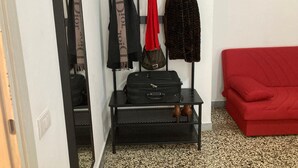 A room with a black metal rack holding bags and scarves, a red sofa, and a painting of a scooter on the wall. - 3 Bagni , 3 Docce, 3 Stanze da Letto nel Centro di Roma (Roma)