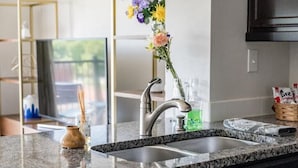 Een keuken met granieten aanrecht, een roestvrijstalen spoelbak en een vaas met bloemen.