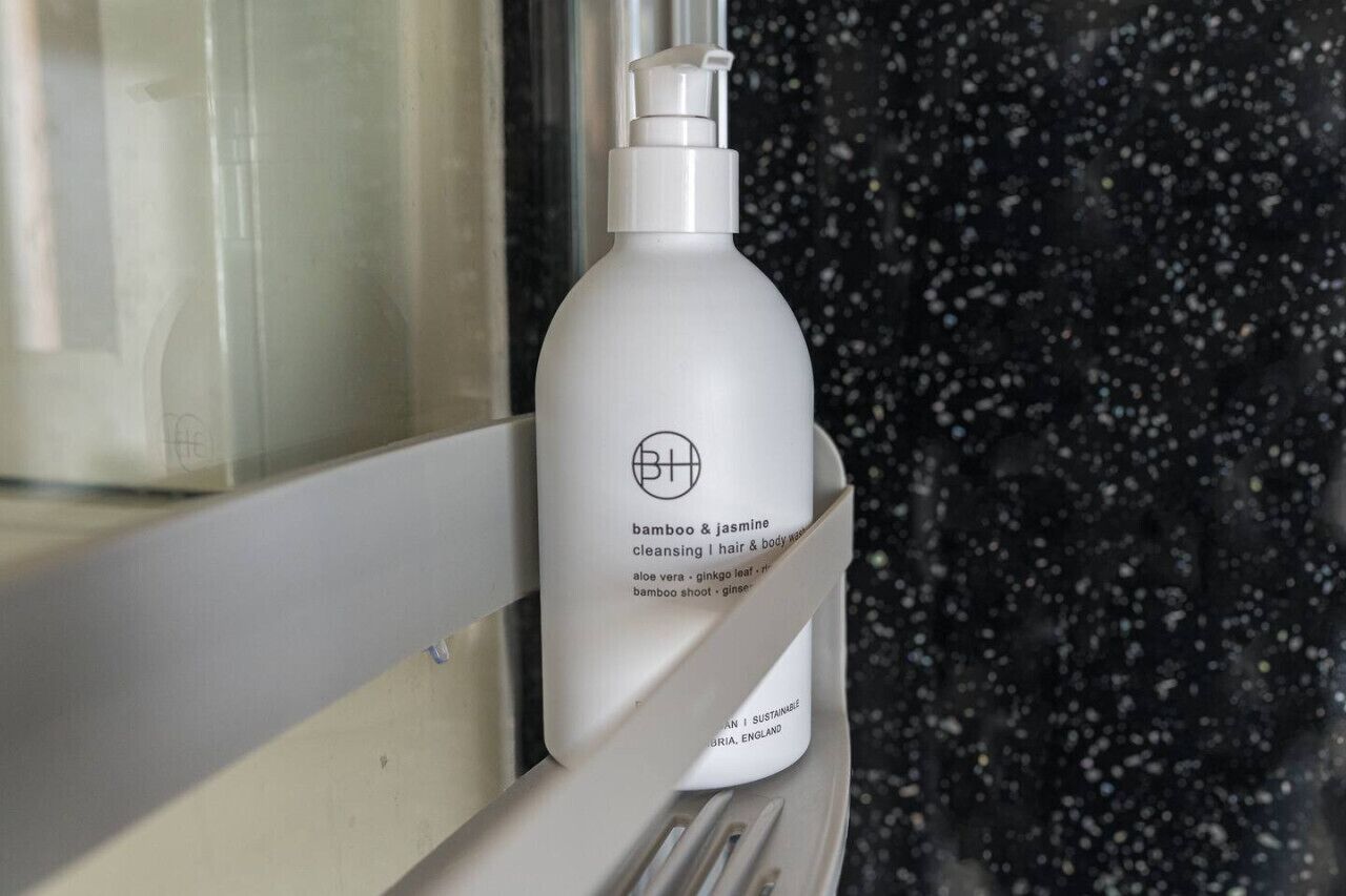 A bottle of bamboo & jasmine cleansing hair & body wash on a window sill.